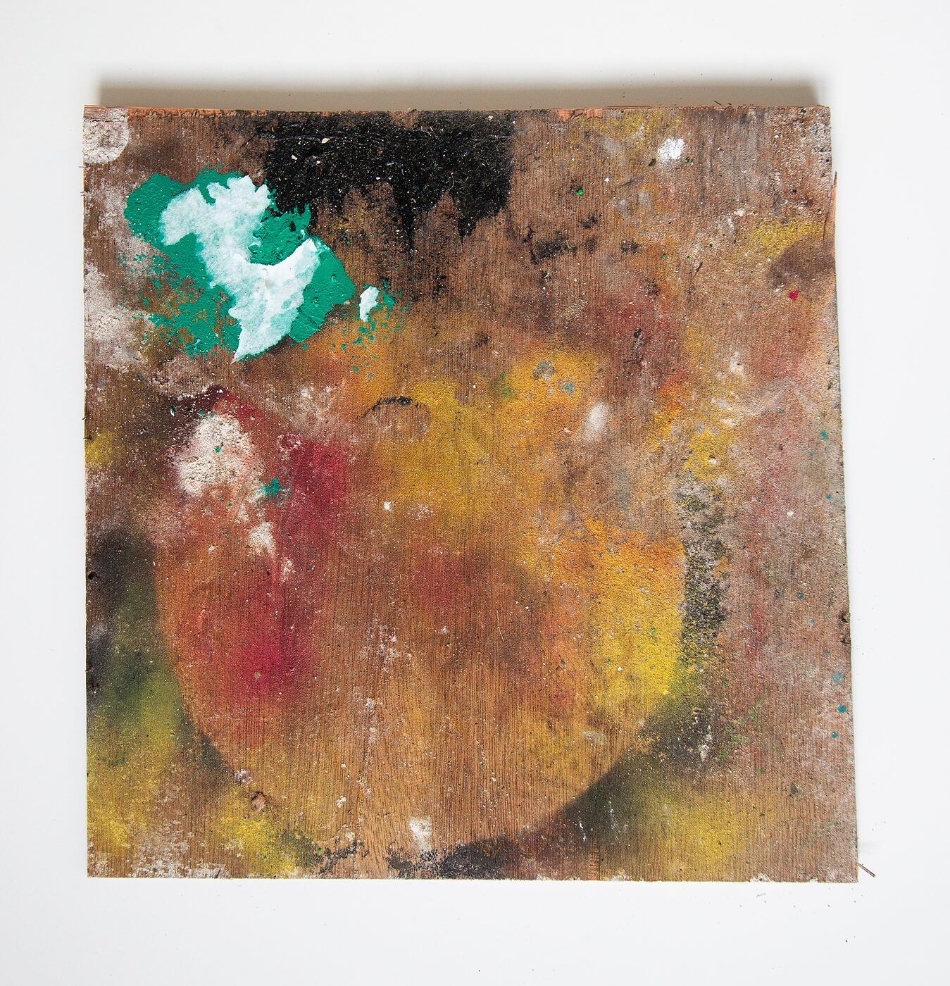 Square masonite. Warm yellow and ochre body filling the centre over a darker red underpainting, with a black mass crowning the top and a hovering green-and-white shape at upper left reading as a ring fragment.