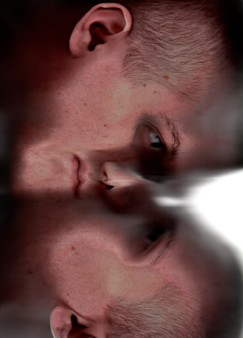 Scanograph: face pressed against flatbed scanner, mirrored and doubled. Intimate, distorted self-portrait through the machine's eye.